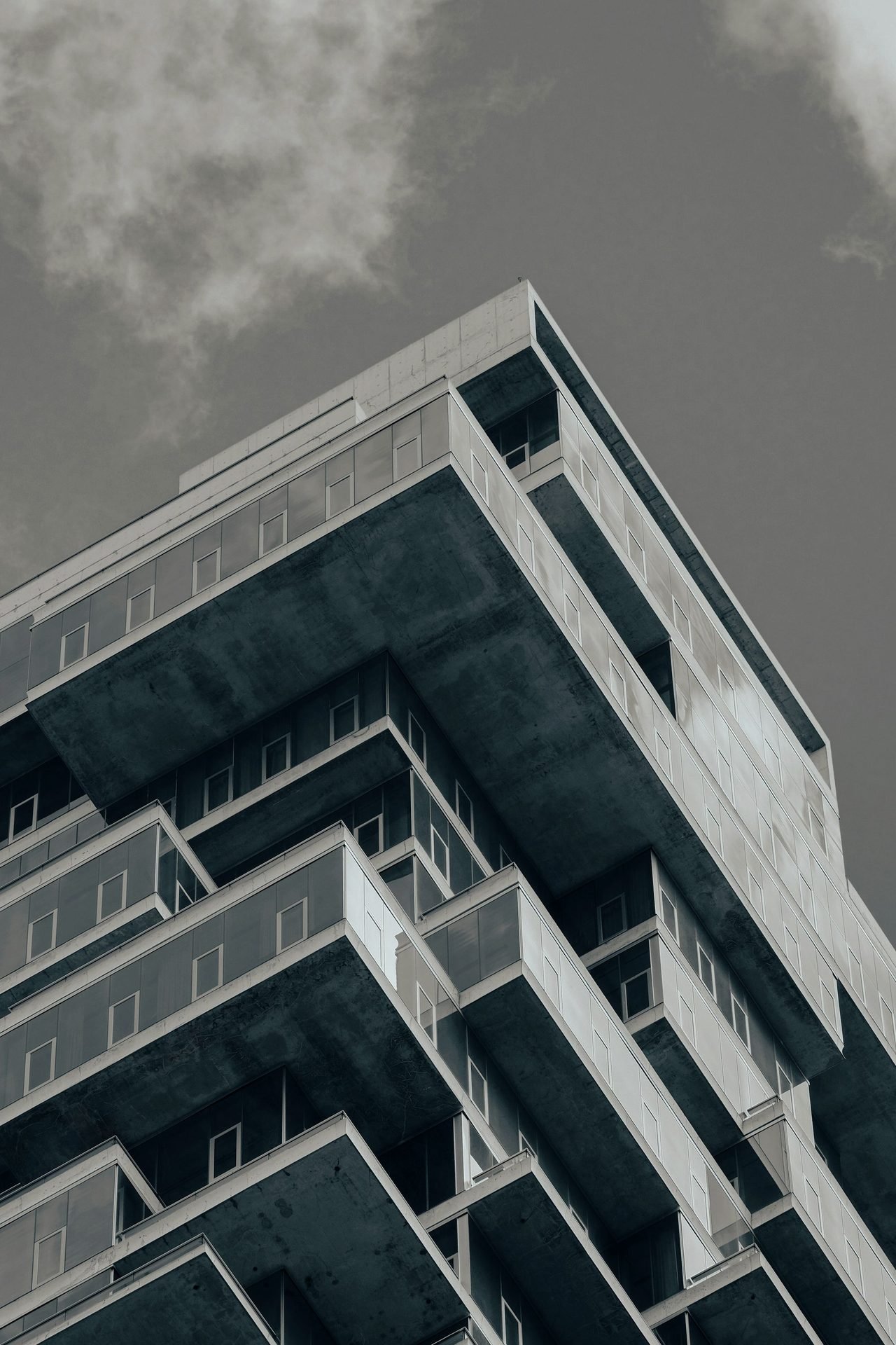 A residential tower photographed from below, balconies stepping up the corner of the building.
